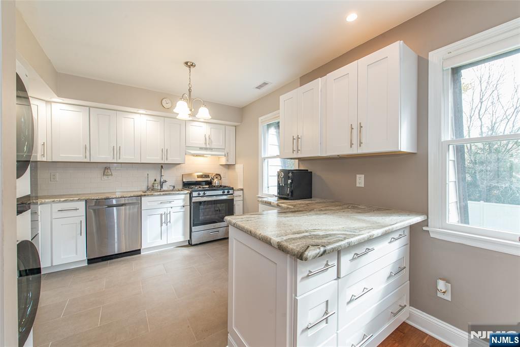 271 Collignon Way, Unit 8B River Vale, NJ 07675 - Photo 11 of 26 a kitchen with a stove a sink a center island and cabinets