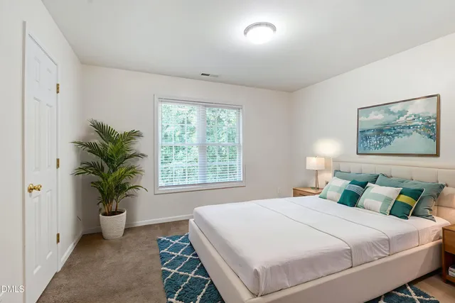 a bedroom with a large bed and a potted plant