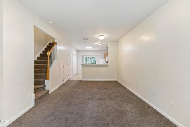 an empty room with a kitchen and entryway