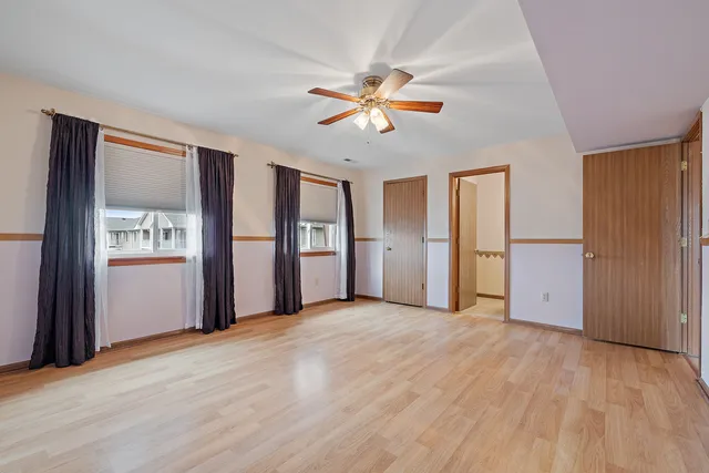 a view of empty room with wooden floor and fan