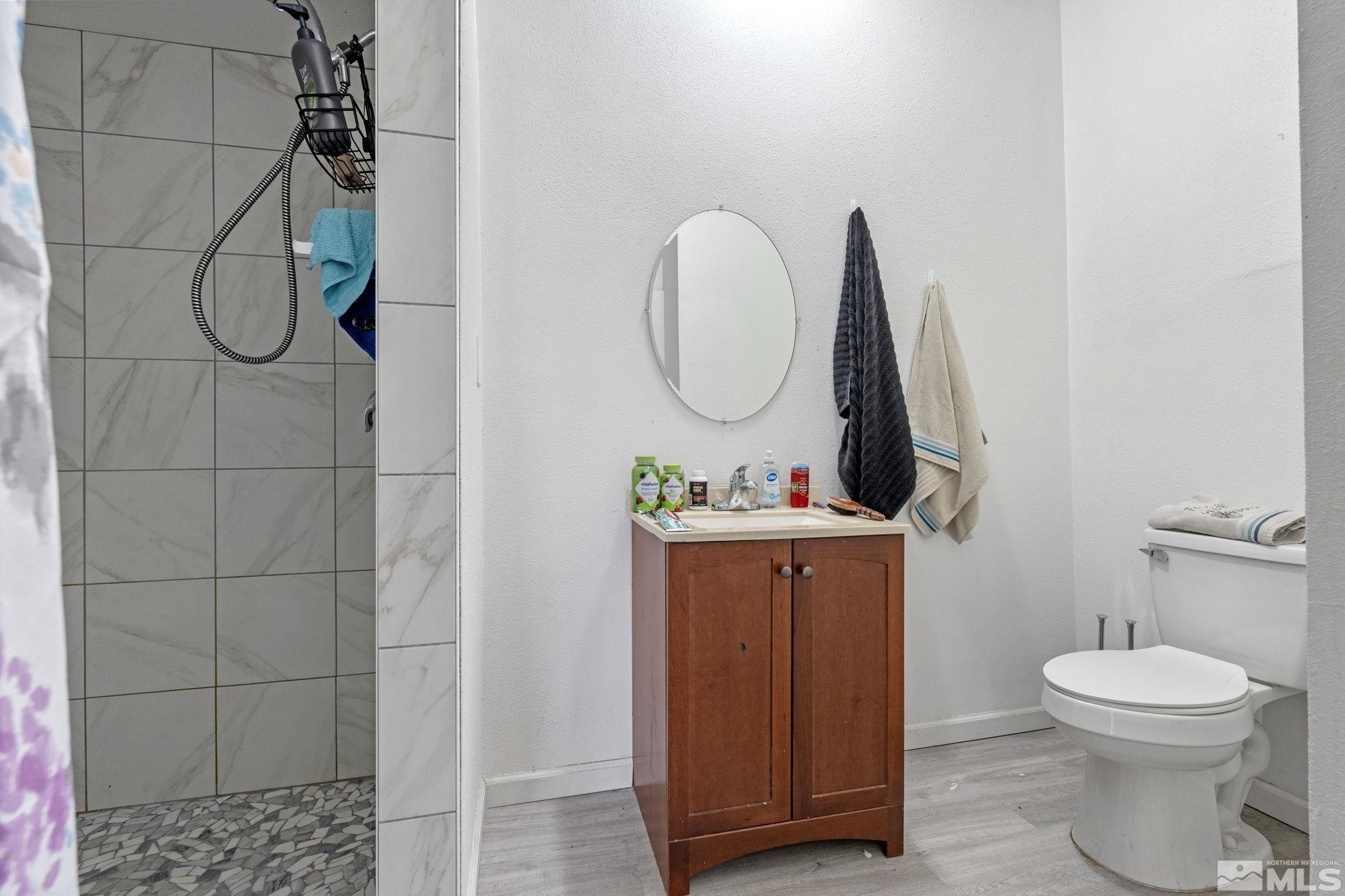 1855 Desna Street Reno, NV 89512 - Photo 25 of 35 a bathroom with a toilet a sink a mirror and shower
