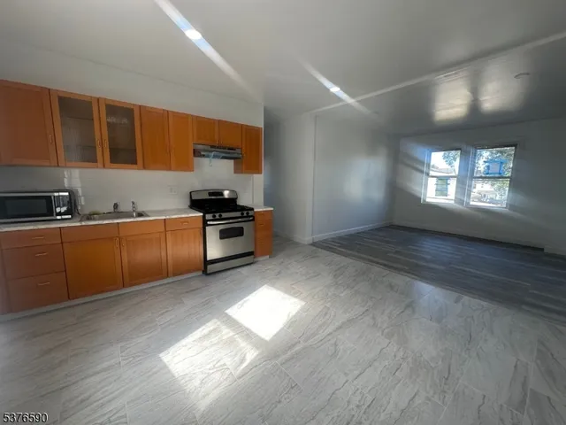 a kitchen with stainless steel appliances granite countertop a sink cabinets and wooden floor