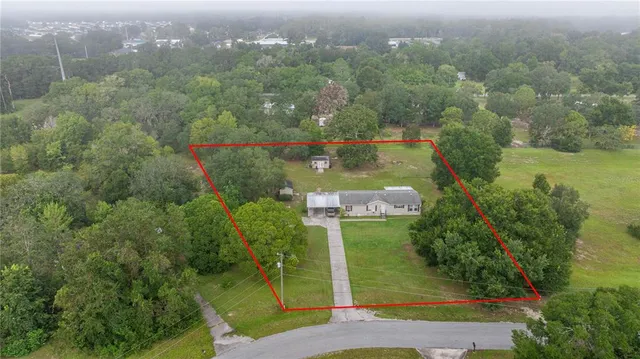 an aerial view of residential houses with outdoor space and trees