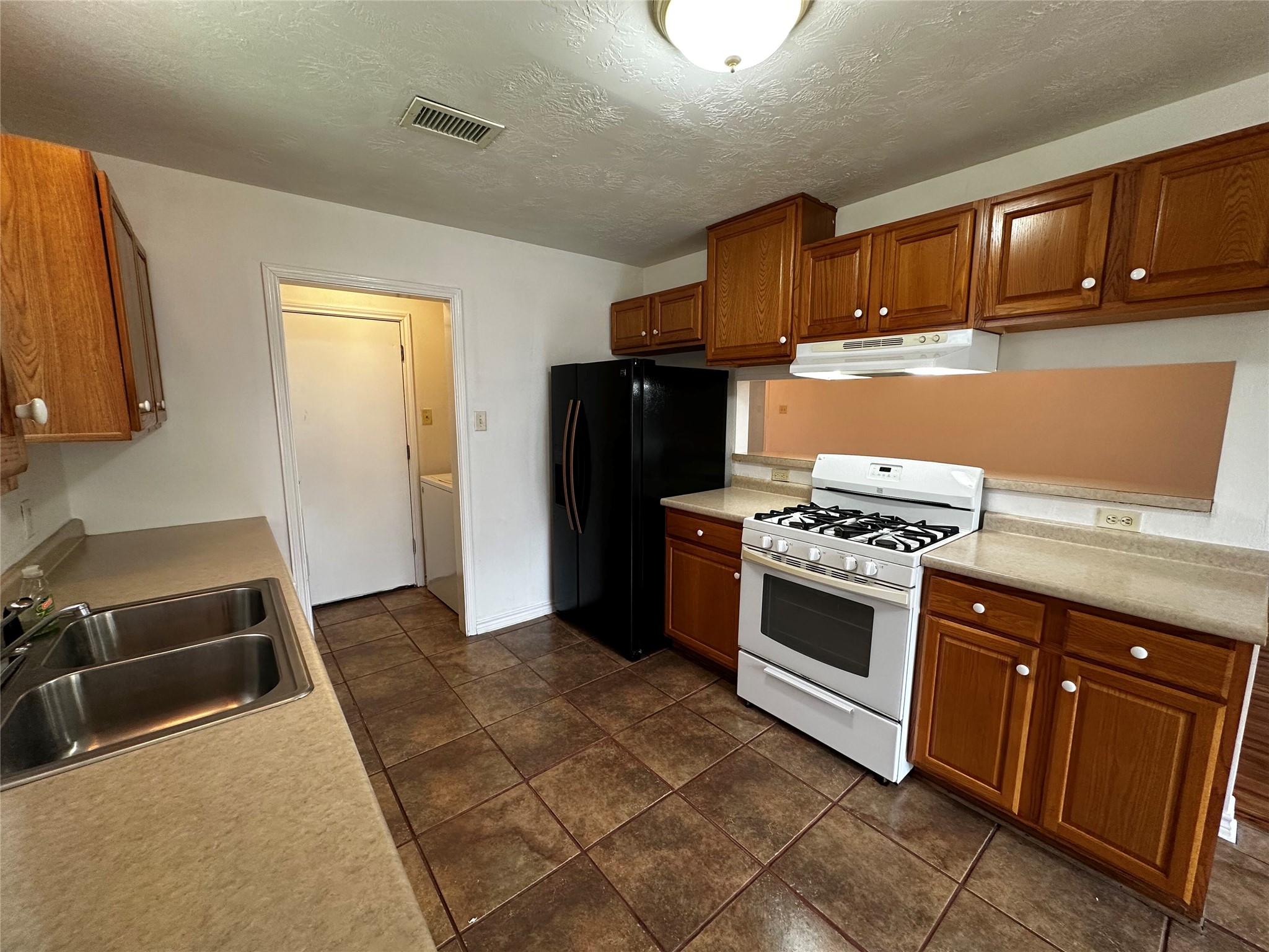 1400 Prairie Drive Bryan, TX 77802 - Photo 7 of 18 A functional kitchen boasts ample cabinetry, a gas range, and durable tile flooring.