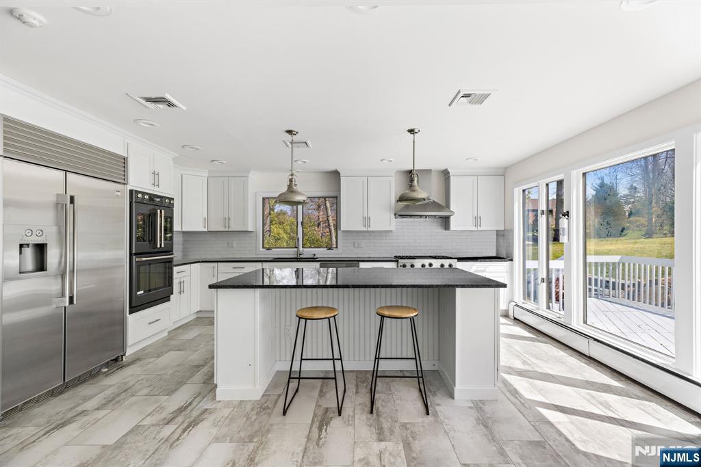 1 Hemlock Drive Cresskill, NJ 07626 - Photo 12 of 26 a kitchen with stainless steel appliances granite countertop a table chairs stove refrigerator and cabinets