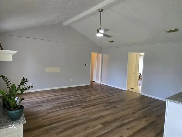a view of an empty room with a window and wooden floor