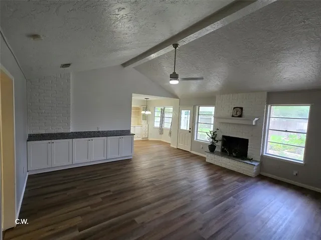 an empty room with windows a fireplace and wooden floor