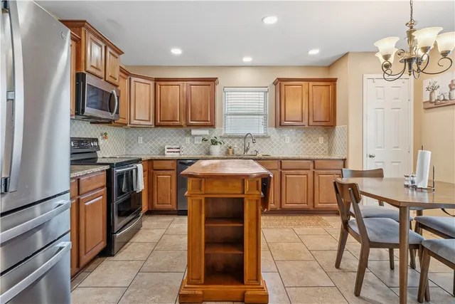 a kitchen with stainless steel appliances granite countertop a stove top oven a sink dishwasher a dining table and chairs with wooden floor