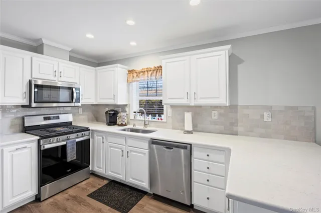 a kitchen with white cabinets stainless steel appliances and sink