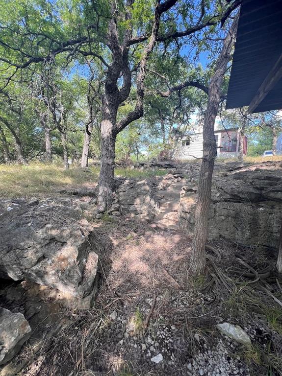 927 Cutter Circle May, TX 76857 - Photo 2 of 23 Natural landscape featuring mature trees, exposed rock formations, and a dirt path