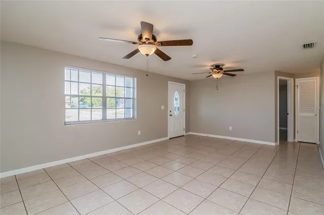 a view of an empty room and window a ceiling fan and closet