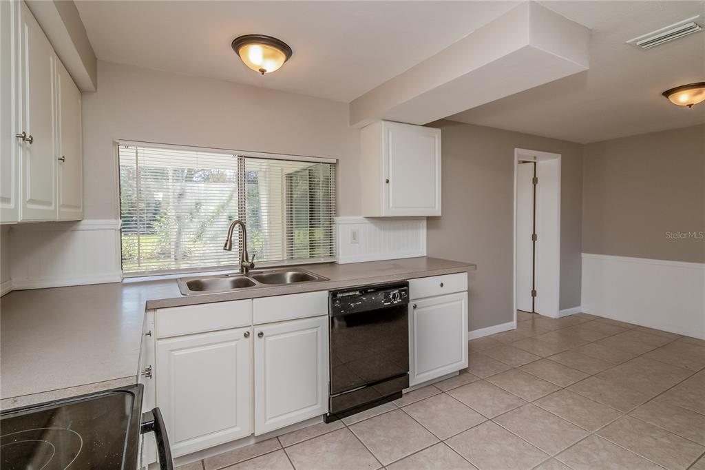 3824 Moog Road Holiday, FL 34691 - Photo 8 of 16 a kitchen with granite countertop white cabinets and white appliances
