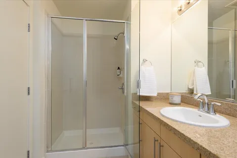 a bathroom with a granite countertop shower sink and mirror