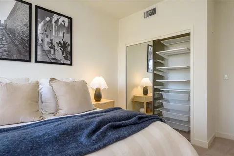 a bedroom with a bed and a lamp on the dresser