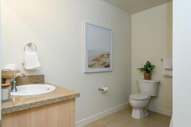 a bathroom with a granite countertop sink and a toilet