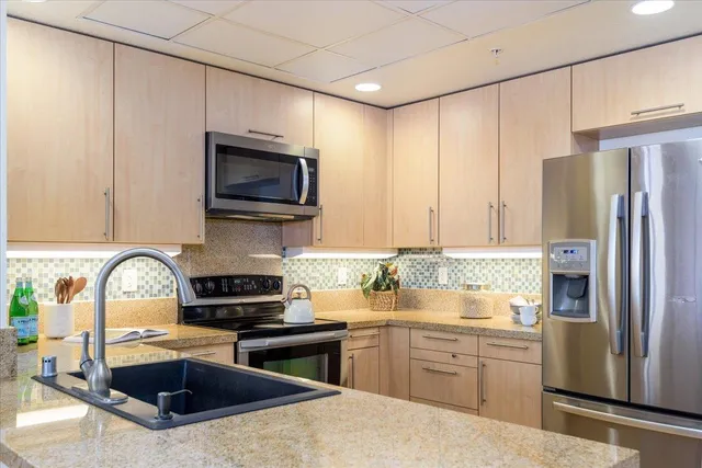 a kitchen with kitchen island granite countertop a sink stainless steel appliances and cabinets