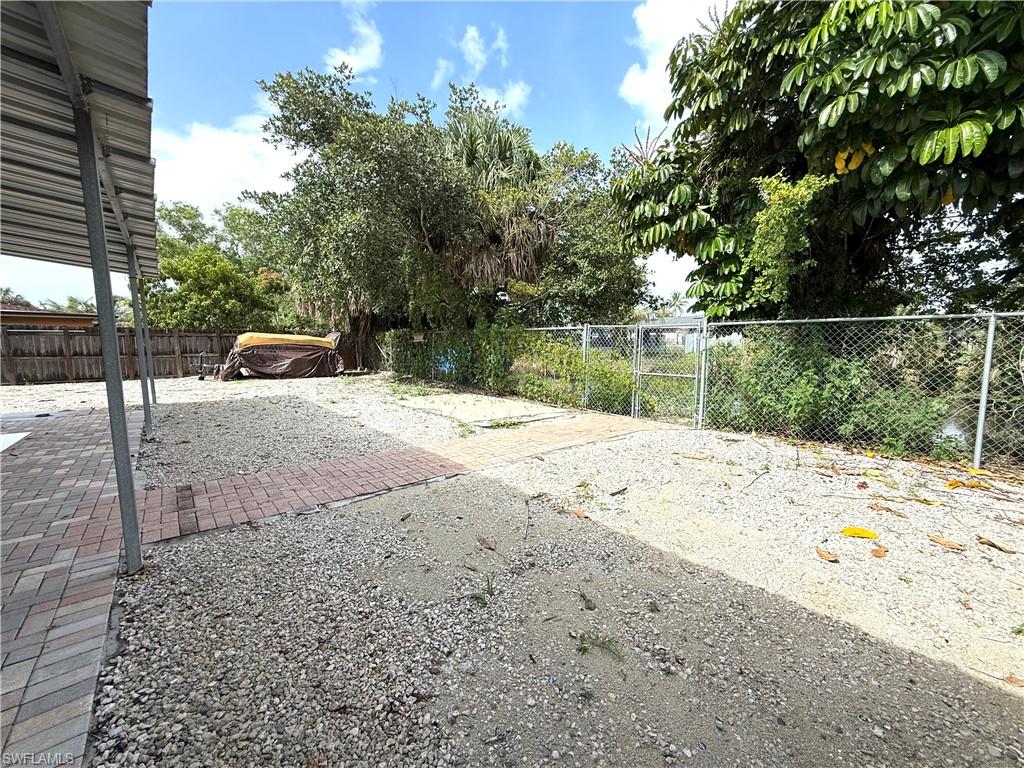 1964 42nd Street Southwest Naples, FL 34116 - Photo 23 of 25 a wooden bench sitting in the middle of a yard