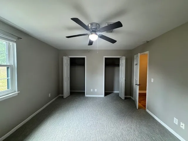 a view of empty room with window and ceiling fan