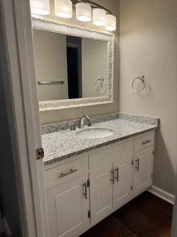 a bathroom with a granite countertop double vanity sink and mirror