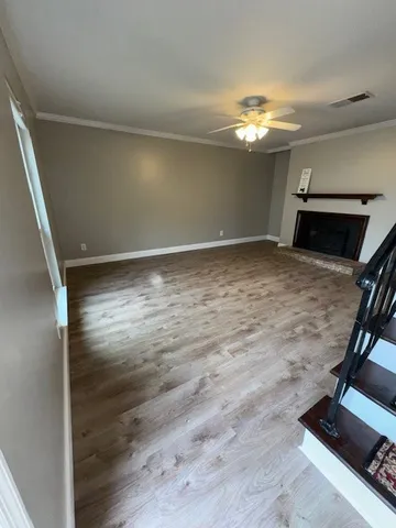 a view of kitchen and empty room with wooden floor