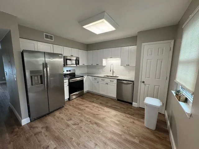 a kitchen with a refrigerator sink and wooden floor