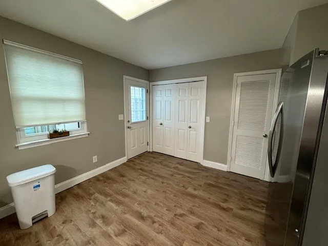a view of an empty room with window and wooden floor
