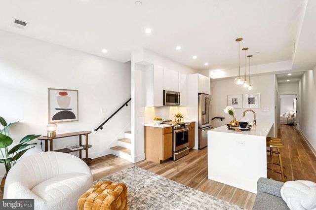 a living room with stainless steel appliances furniture and a view of kitchen