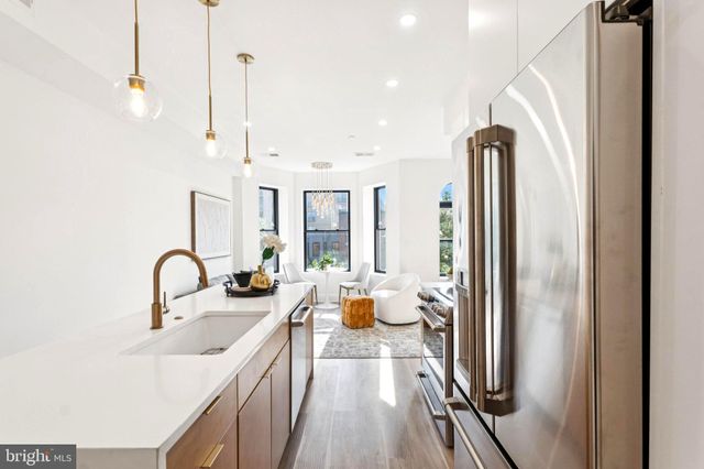 a kitchen with stainless steel appliances a sink a counter top space and a view of living room