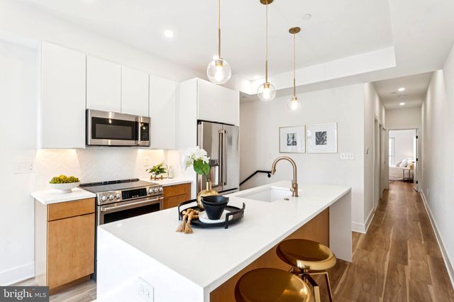 a kitchen with a sink a stove and chairs with wooden floor