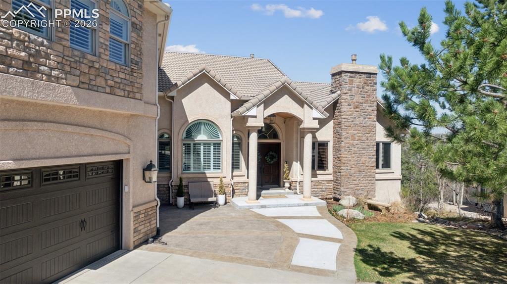 5039 Stonehill Road Colorado Springs, CO 80918 - Photo 2 of 50 French provincial home featuring stucco siding, driveway, a chimney, and a garage