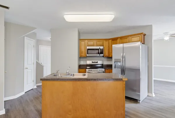 an empty room with wooden floor chandelier fan and windows
