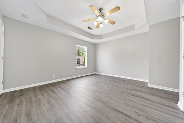 an empty room with wooden floor and windows