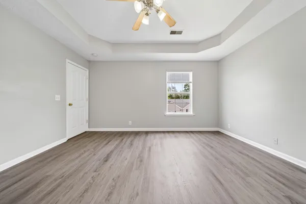a view of an empty room with window and wooden floor