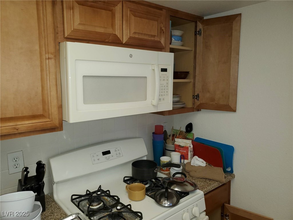 8070 West Russell Road, Unit 1005 Las Vegas, NV 89113 - Photo 8 of 12 Kitchen with white appliances, brown cabinets, and decorative backsplash