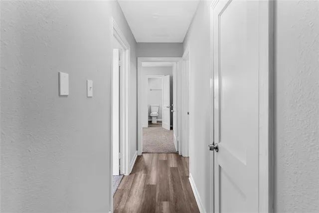 a view of a hallway with wooden floor and closet area