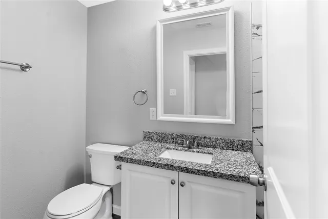a bathroom with a granite countertop sink toilet and mirror