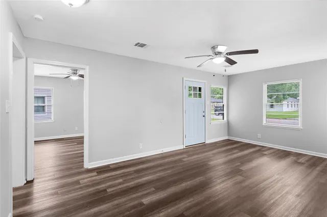a view of an empty room with a window and wooden floor