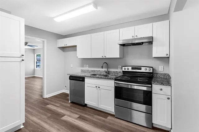 a kitchen with granite countertop wooden floors and white stainless steel appliances