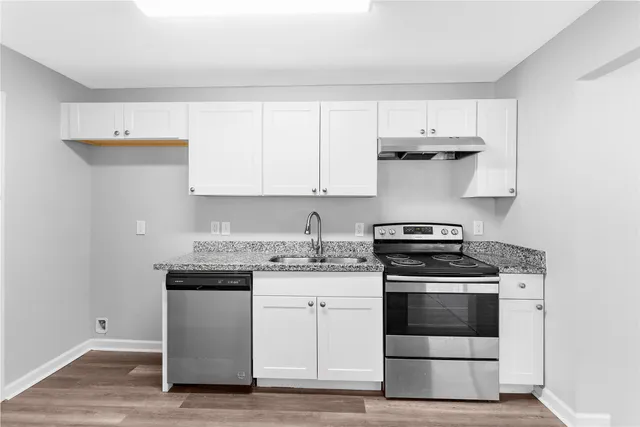 a kitchen with stainless steel appliances granite countertop a stove and white cabinets