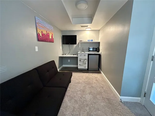 a living room with stainless steel appliances kitchen island furniture and a flat screen tv