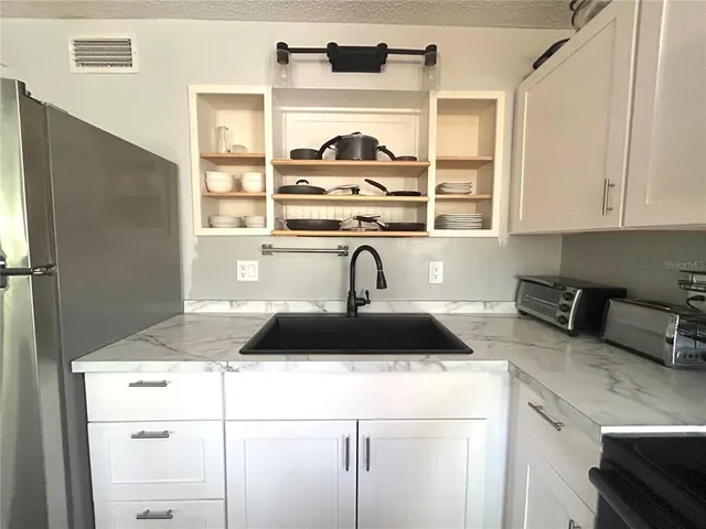 a view of a kitchen counter space a sink wooden floor and cabinets