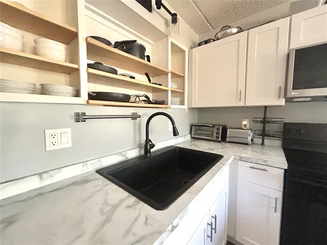 a kitchen with stainless steel appliances granite countertop a sink a stove and a microwave