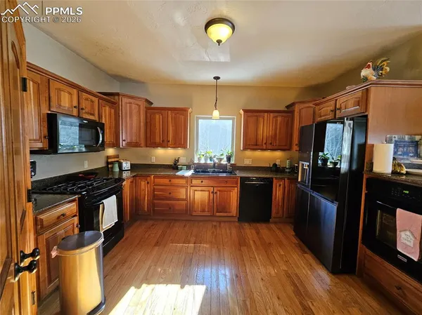 a kitchen with granite countertop a refrigerator stove top oven and sink