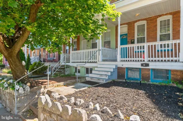 a front view of a house with a yard tree and wooden fence