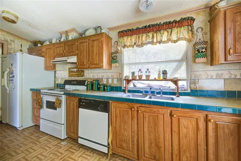 a kitchen with stainless steel appliances granite countertop a refrigerator a sink dishwasher and white cabinets with wooden floor