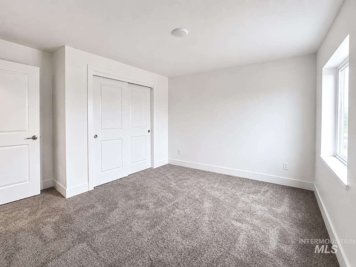 8098 West Fern Street Eagle, ID 83616 - Photo 11 of 22 Neutral-toned carpeted room featuring a white interior door, sliding closet doors, a single window, and a flush-mount ceiling light fixture