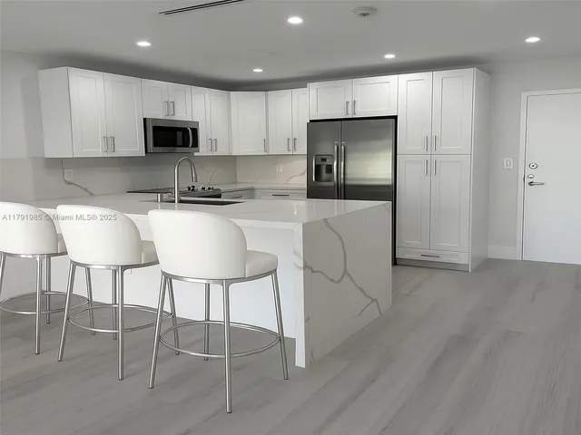 a kitchen with kitchen island white cabinets and stainless steel appliances