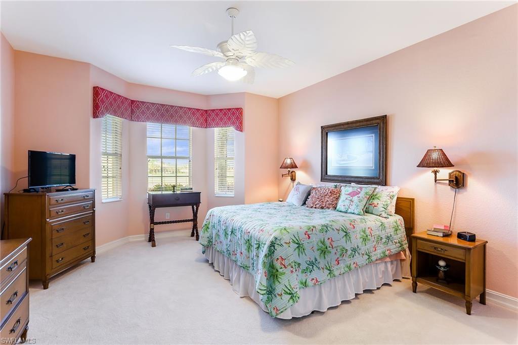 8609 Champions Point, Unit 201 Naples, FL 34113 - Photo 17 of 25 a bedroom with a bed and a chandelier