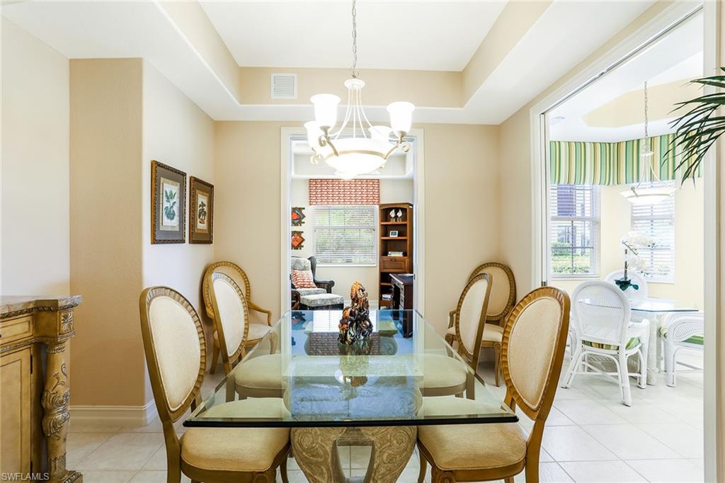 8609 Champions Point, Unit 201 Naples, FL 34113 - Photo 4 of 25 a view of a dining room with furniture a chandelier and large windows