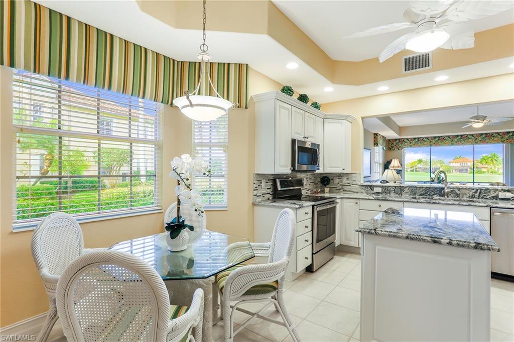 8609 Champions Point, Unit 201 Naples, FL 34113 - Photo 9 of 25 a kitchen with stainless steel appliances granite countertop a stove a refrigerator a sink dishwasher with a dining table and chairs